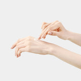 A hand gently applies a creamy, white serum to another hand, showcasing the luxurious texture of Sulwhasoo's Concentrated Ginseng Brightening Serum and its potential to enhance skin radiance and elasticity.